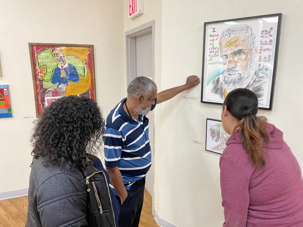 BronxWorks Supportive Housing resident Peter J. discusses two of his art pieces with some gallery attendees.
